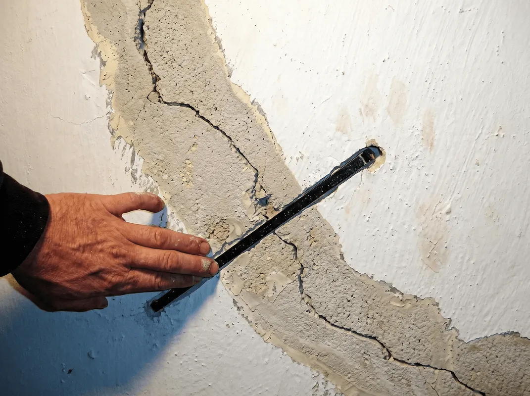 A wall with a large crack is being inspected by a professional in West Palm Beach, FL