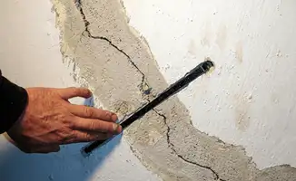 A wall with a large crack is being inspected by a professional in West Palm Beach, FL